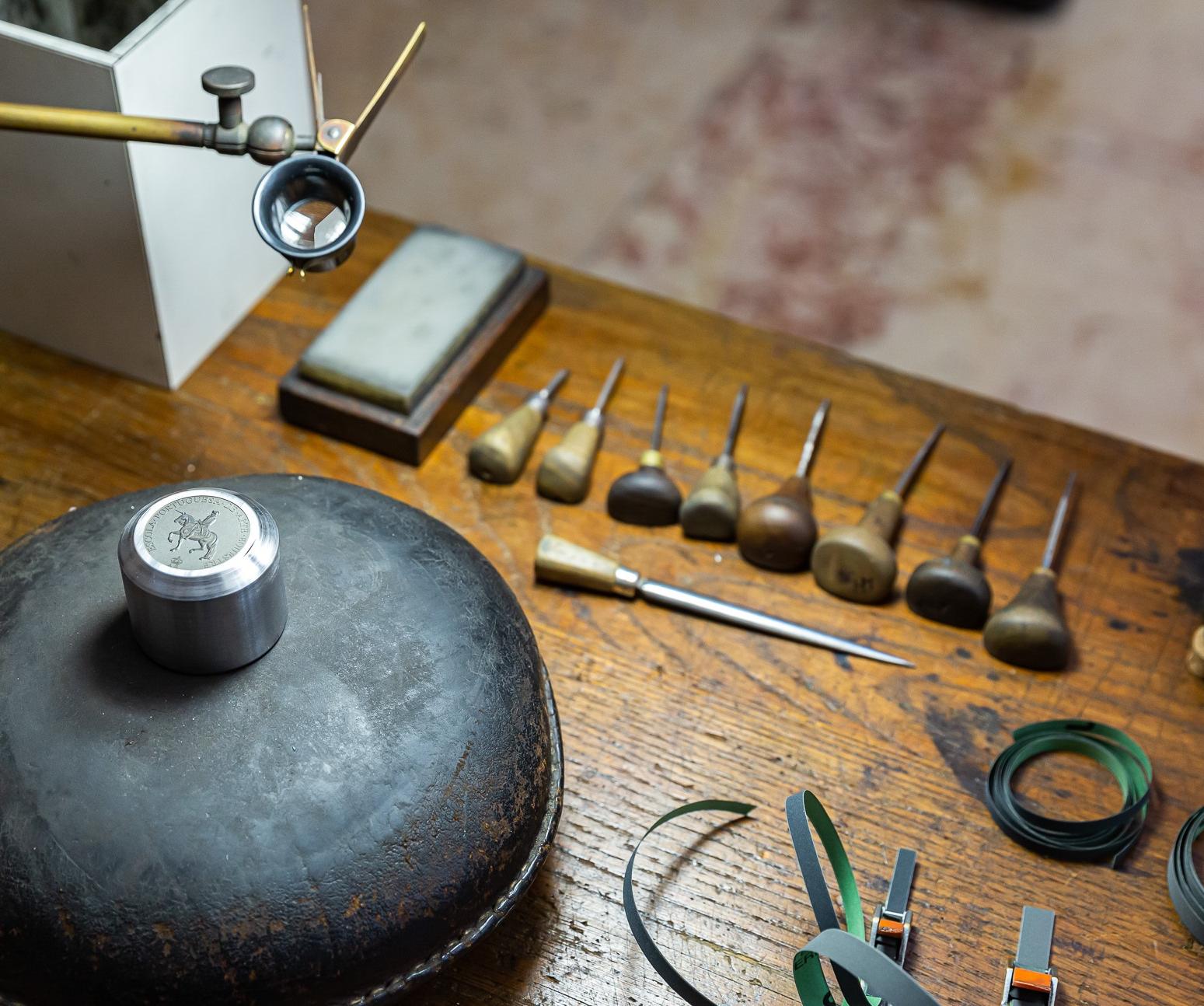 Várias ferramentas de trabalho para fazer cunhos, em cima de uma mesa de madeira